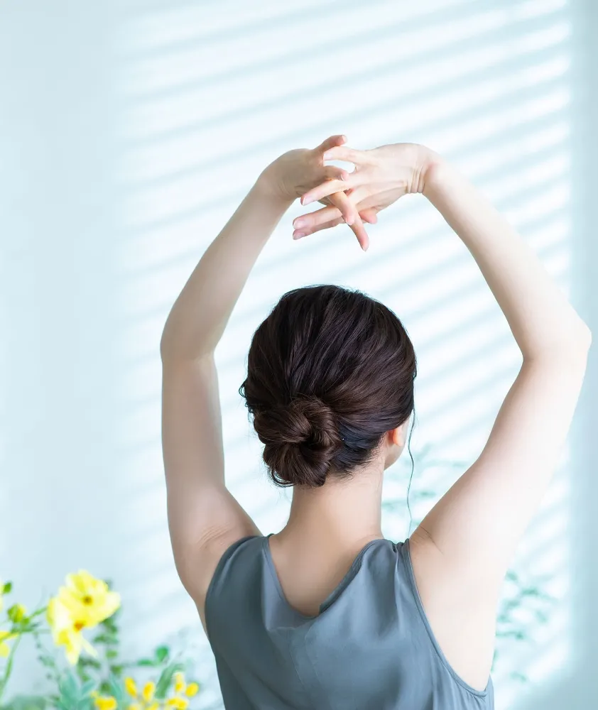 伸びをしている背中向きの女性